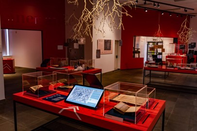 Innenansicht des Schopenhauer-Studios, im Vordergrund ein Ausstellungstisch mit Büchern in Vitrinen und einem Bildschirm, von der Decke hängen Äste